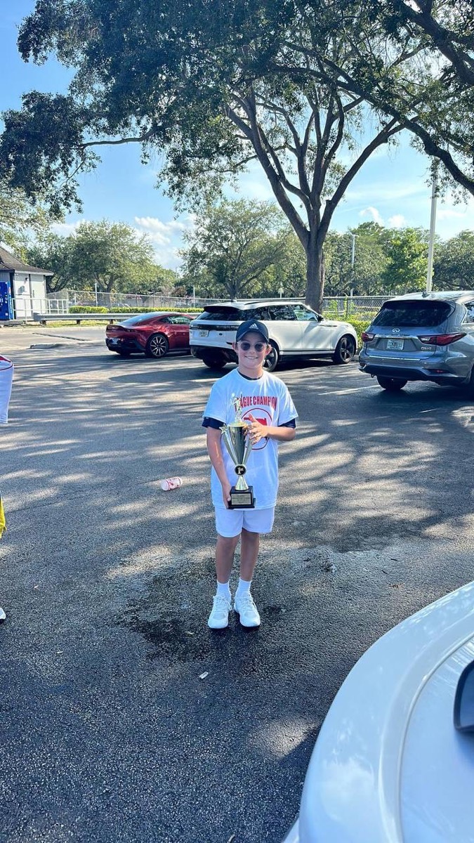 Alex holding a league champion trophy after a tournament