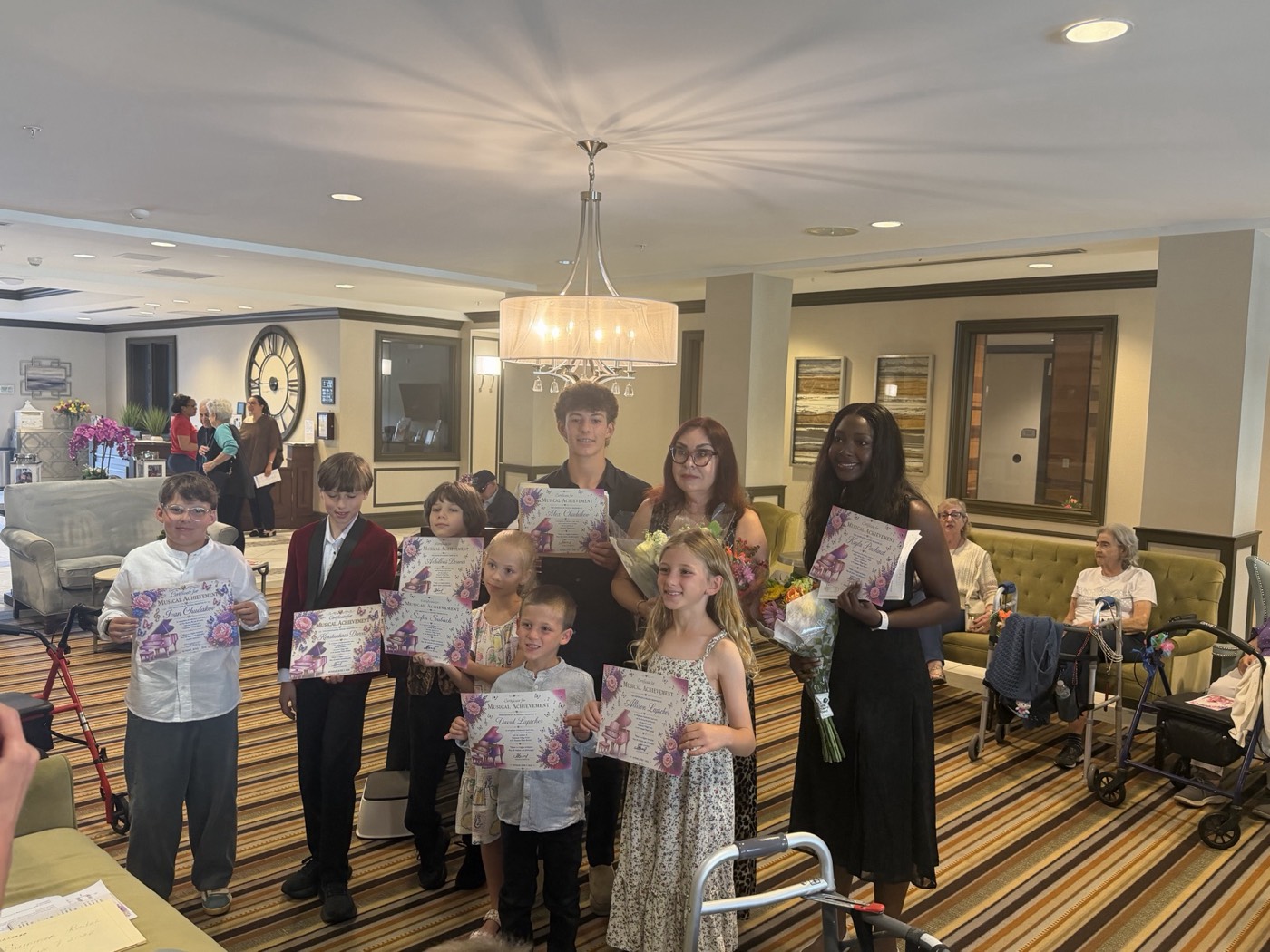 Alex and fellow piano students holding Musical Achievement certificates after their community recital at Oakmonte Village Senior Living